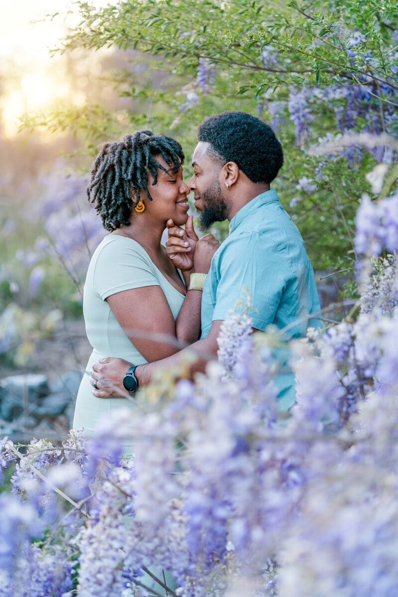 LaVianca and Shakim are nose to nose among a sea of purple wisteria flowers.