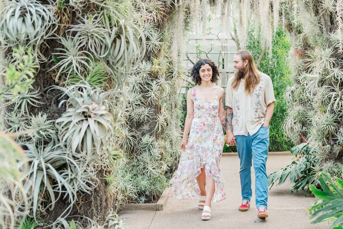 Couple walking hand-in-hand through the succulent arches in the Orchid Conservatory