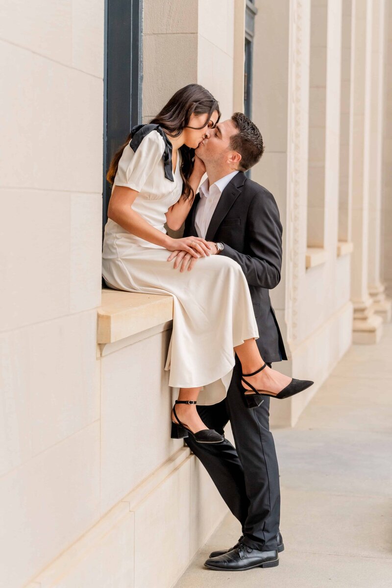 Couple leaning against white columns for urban engagement portrait