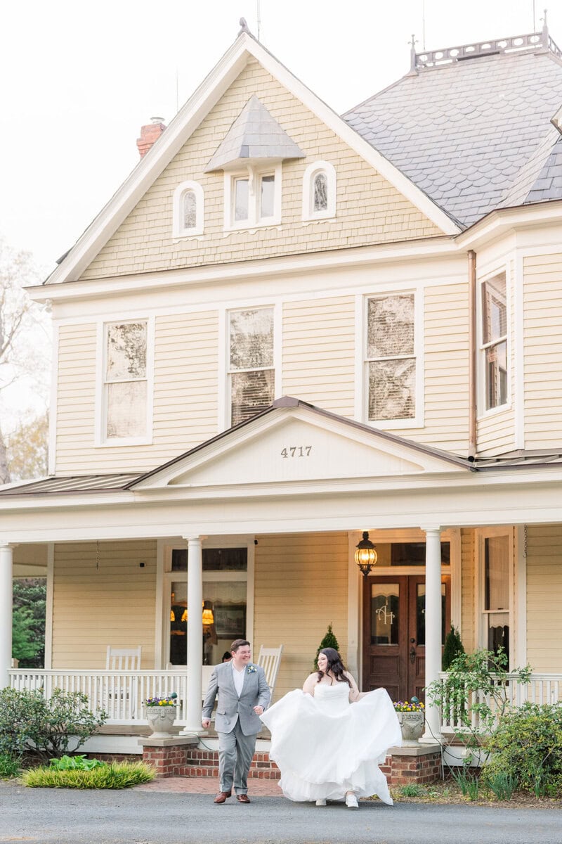 Bride holding skirt in both hands in front of Alexander Homestead manor