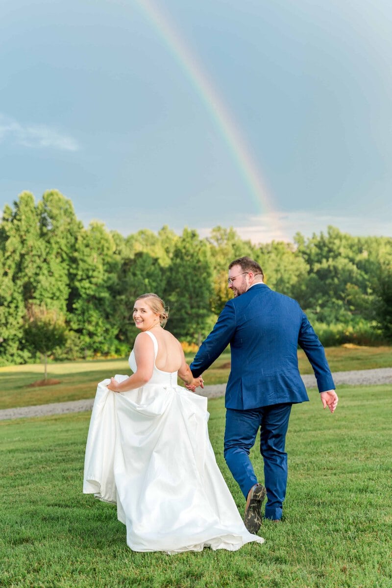 Charlotte NC wedding photographer captures newly weds running towards a rainbow on their wedding day