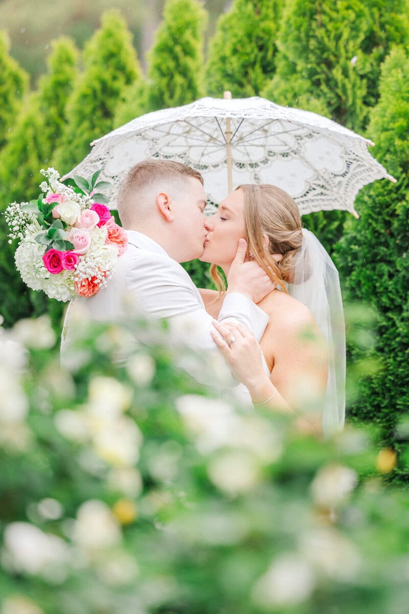 Couple kisses in the rain on their wedding day captured by the lilac lion photography, listed as one of the best photographers in charlotte nc