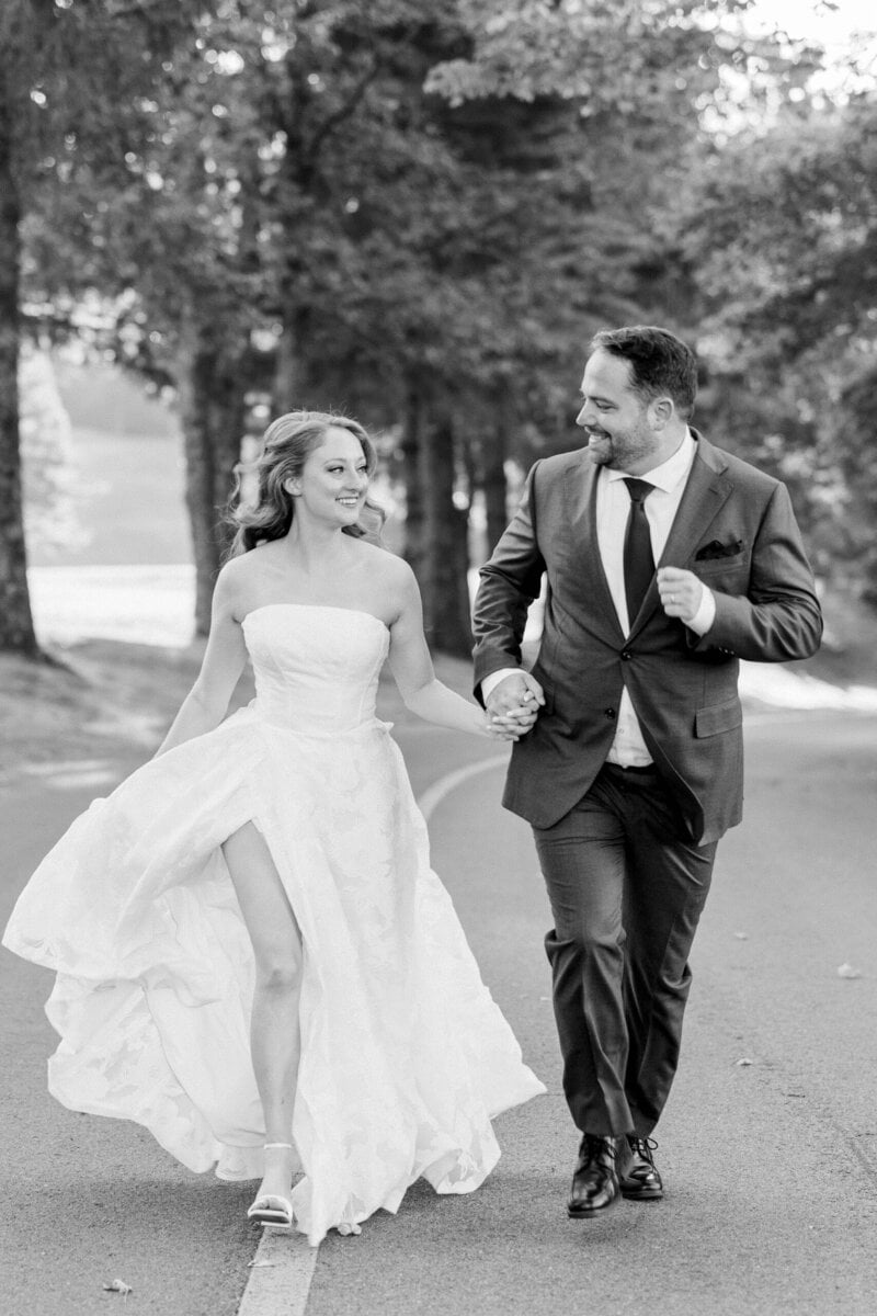couple runs down the road towards the camera during golden hour on their wedding day