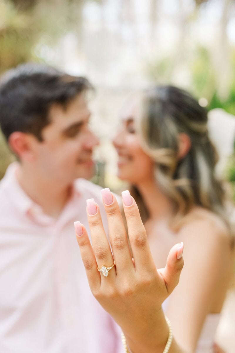 Woman looking at engagement ring after surprise proposal inside Daniel Stowe Botanical Garden Orchid Conservatory photographed by Charlotte proposal photographer The Lilac Lion Photography