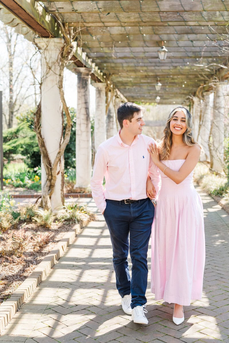Couple in coordinating pink outfits during engagement portraits at Daniel Stowe Botanical Garden photographed by The Lilac Lion Photography Charlotte NC wedding photographer