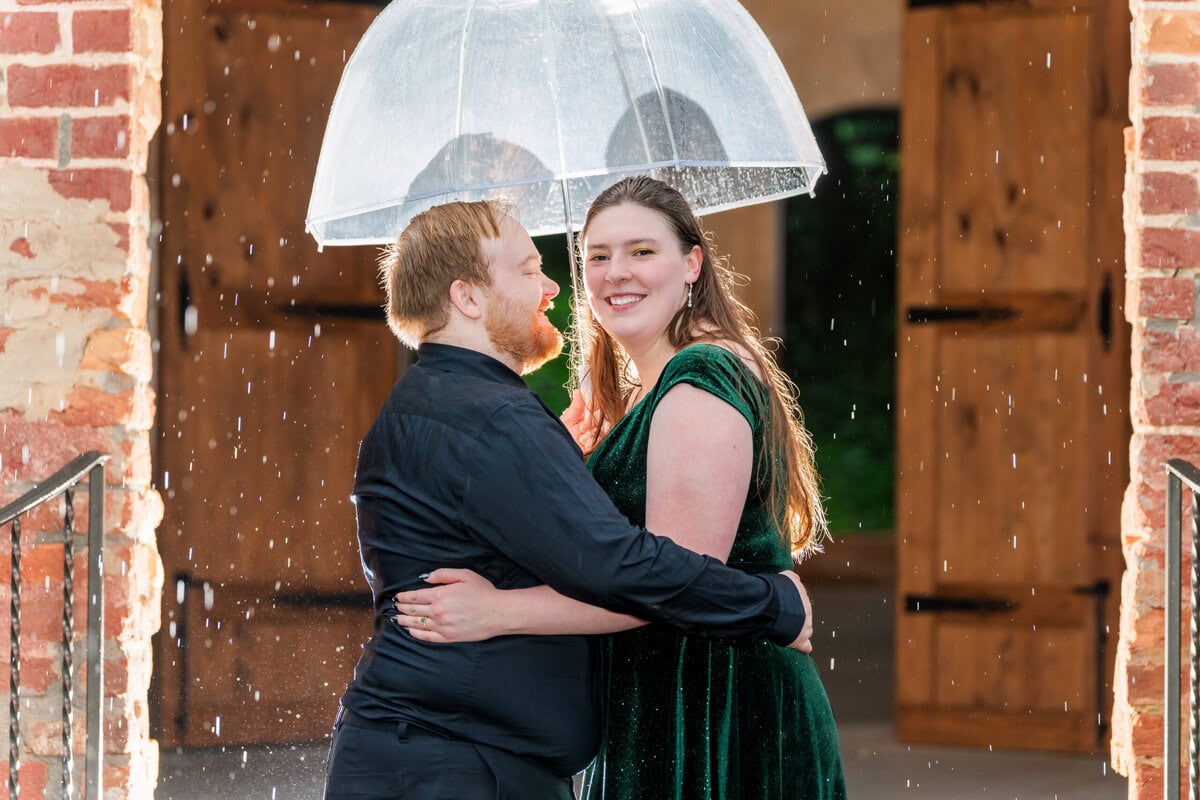 Rainy day engagement photos at historic venue outside Charlotte NC with flash and clear umbrellas