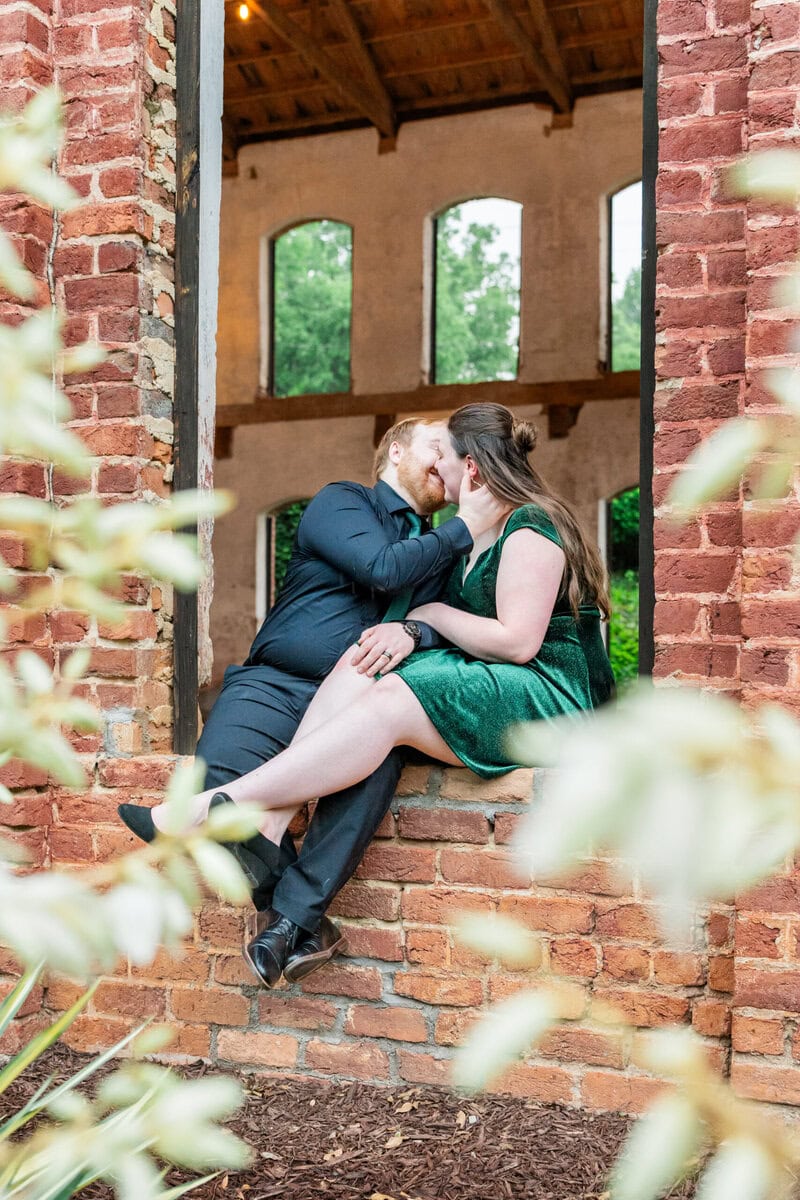 Couple framed by arched windows at The Providence Cotton Mill engagement session near Lake Norman NC