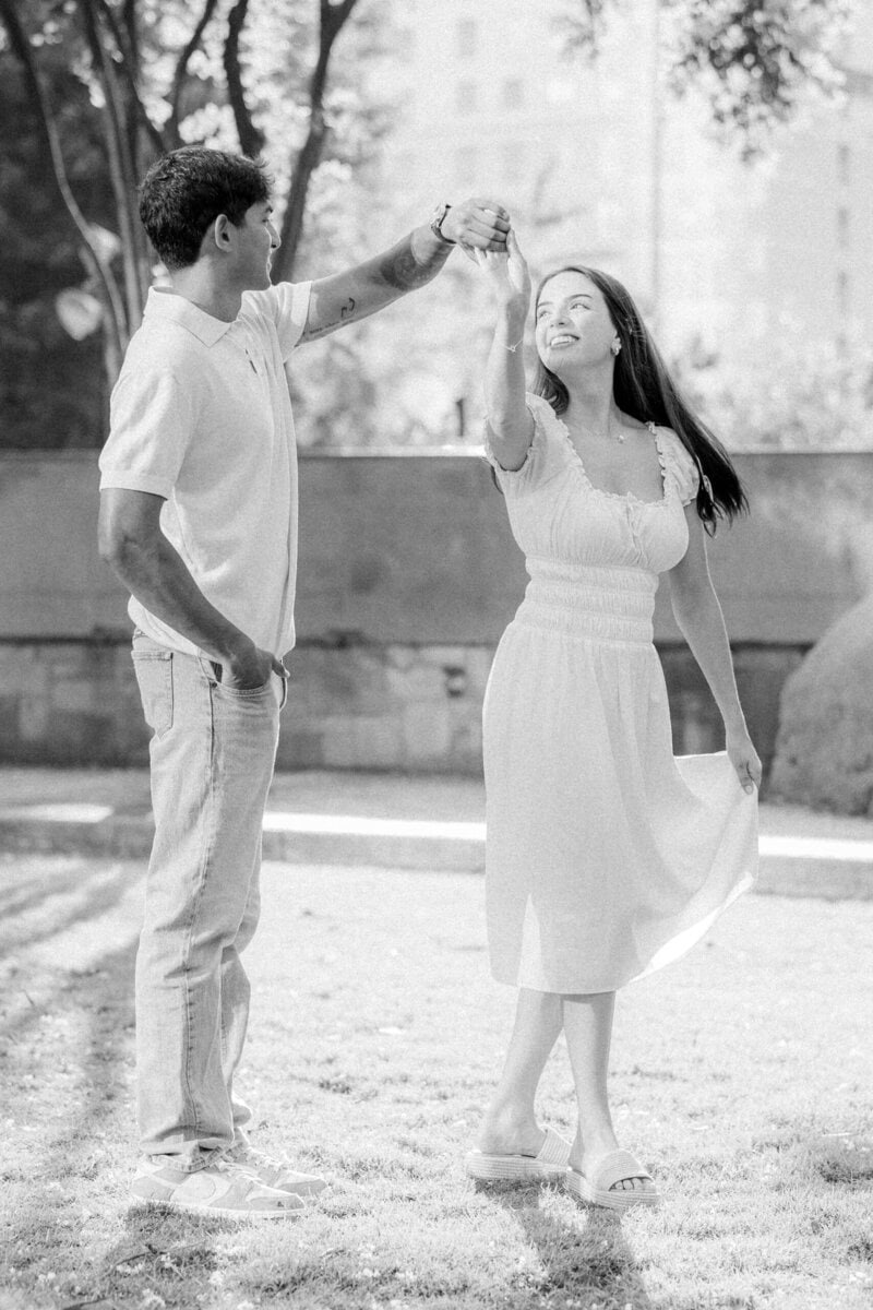 Groom to be spinning fiancee in white dress in Uptown Charlotte park