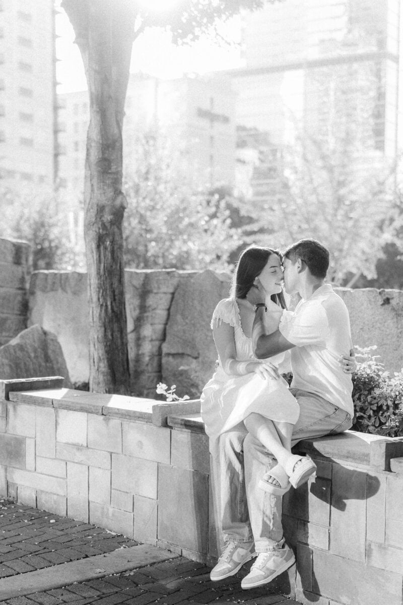 Couple kissing on stone wall near Romare Bearden Park during golden hour