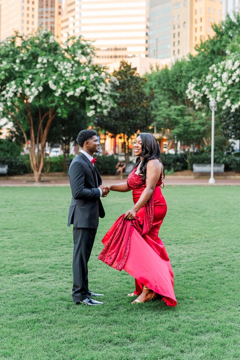 Bride to be in red dress laughing with fiance in downtown Charlotte engagement session