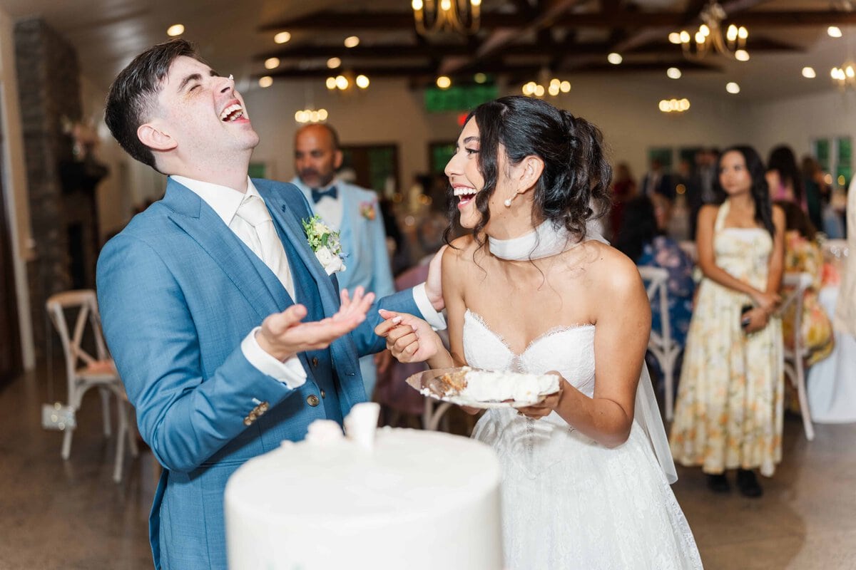 Bride and groom laughing after breaking the knife cutting their wedding cake