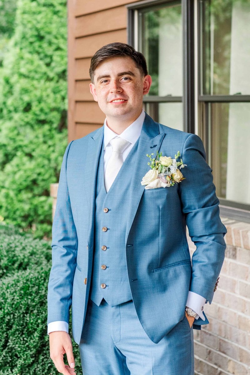 Groom in a slate blue suit outside the bridal suite at Rolling Hill Venue