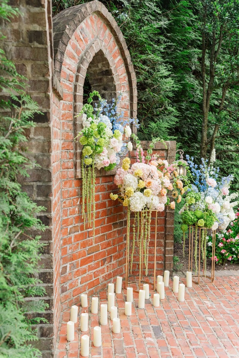 Brick arch ceremony setup with pastel florals and candles at Rolling Hill Venue in Monroe NC