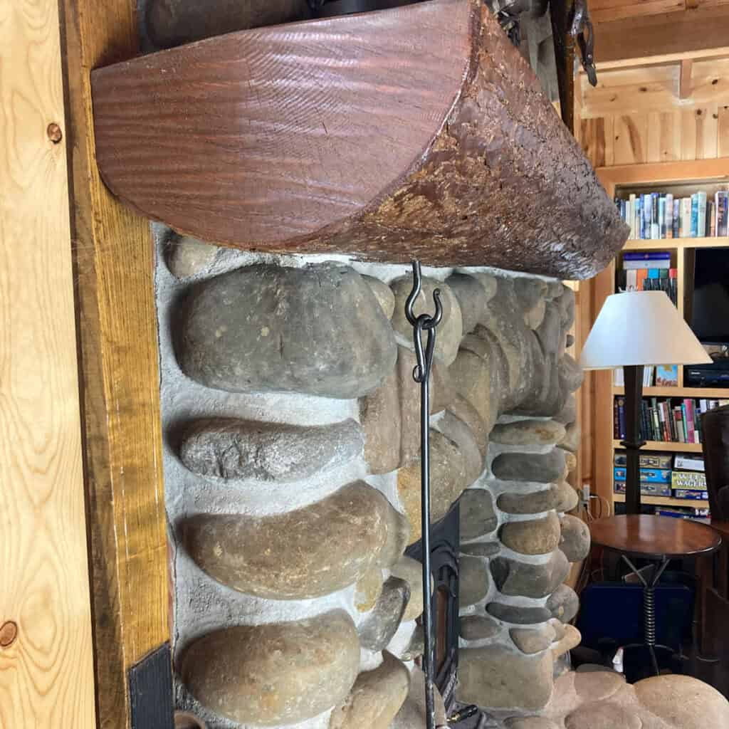 Stone fireplace with a wood mantle and fire poker hanging from hook.