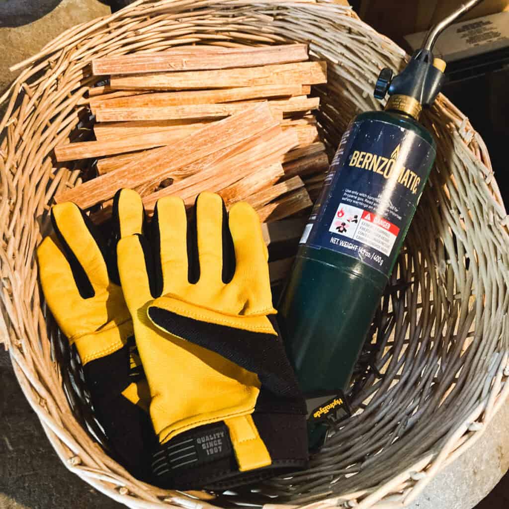 basket with fatwood, propane torch, leather gloves for wood stove.