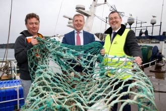 Fishermen with fishing gear on a fishing vessel at port, commercial fishing industry publication.