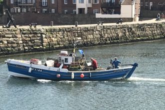 Fishing vessel with crew working near port, commercial fishing industry scene.