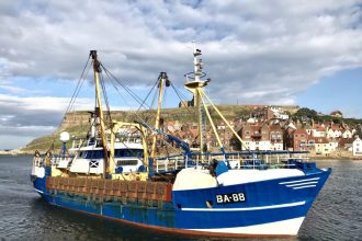 Fishing vessel with gear and industry equipment in port, commercial fishing industry publication, UK.
