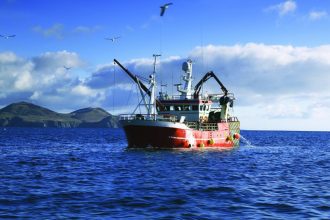 Fishing vessel at sea in a commercial fishing industry publication, with gear and industry equipment.