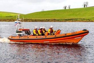 Commercial fishing industry publication: RNLI rescue boat with crew on river.