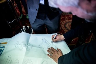 Fishermen reviewing vessel blueprints at a commercial fishing industry event.