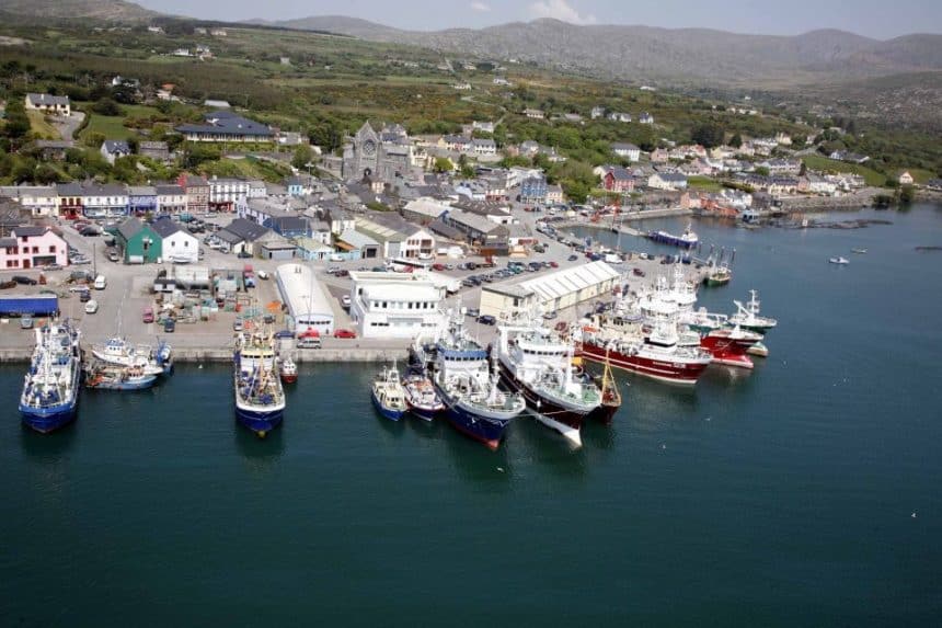 Fishing vessels docked at a busy commercial port with industry equipment and gear visible.