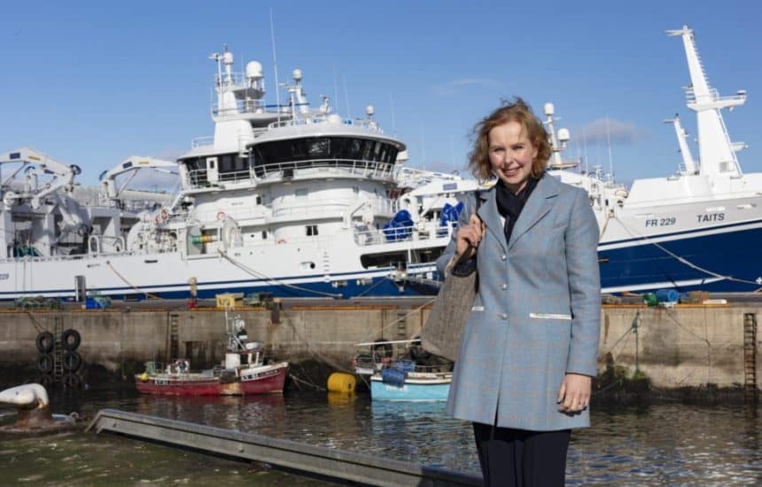 Woman standing by fishing vessels at port, commercial fishing industry publication.