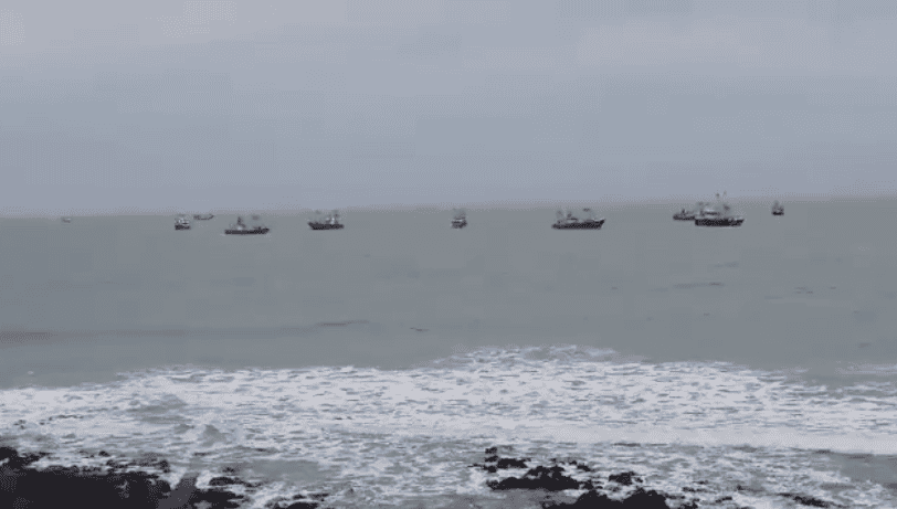 Fishing vessels at sea in a commercial fishing industry setting, with overcast sky.