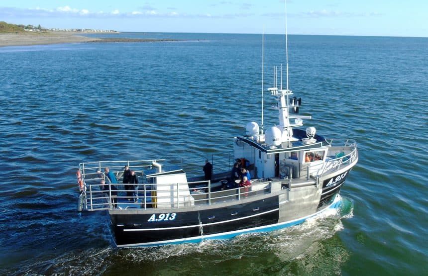 Fishing vessel with crew on deck in open sea, commercial fishing industry context.