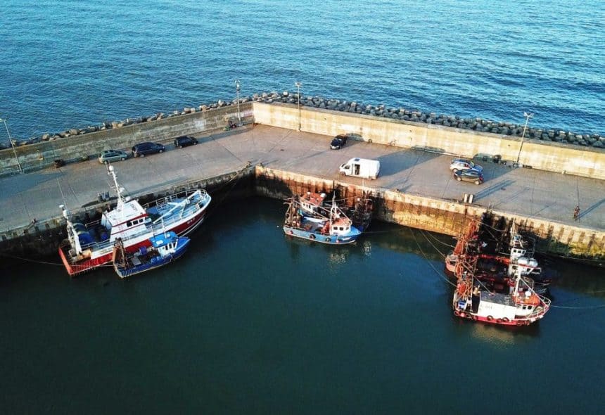 Fishing vessels docked at port in a commercial fishing industry setting, with gear and industry gear.