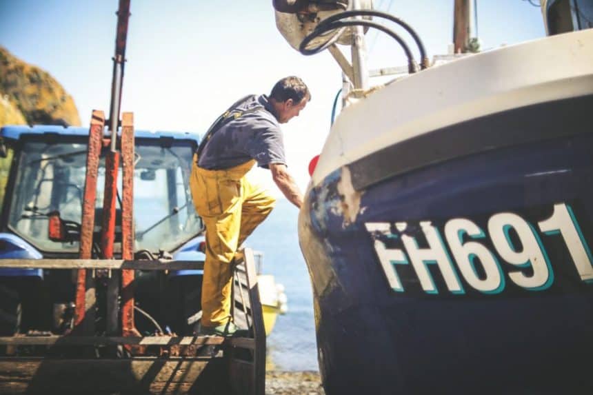 Fishermen inspecting fishing vessel at port, industry equipment, commercial fishing scene.