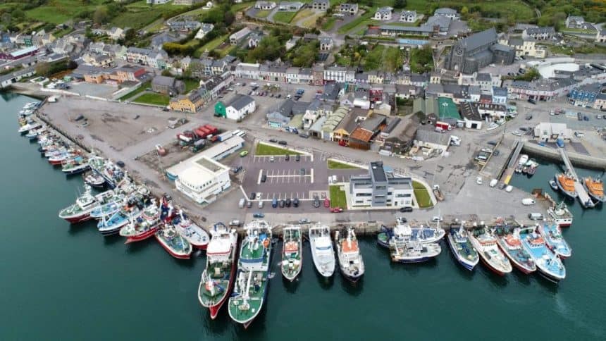 Aerial view of fishing vessels docked at a commercial port, industry equipment visible, in a fishing.