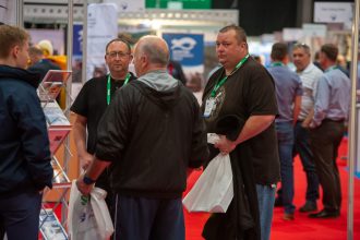 Fishing industry exhibition with fishermen discussing gear and vessels at a trade show.