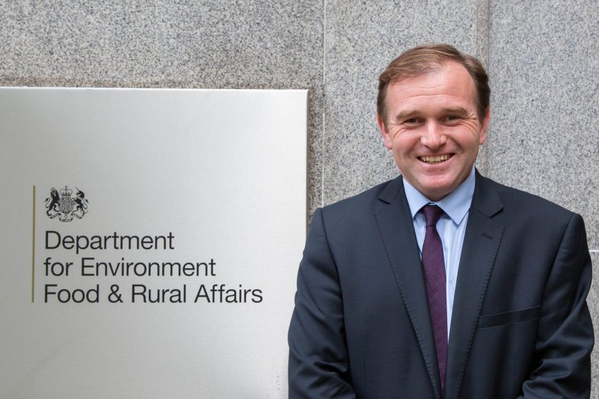 Official at Department for Environment, Food & Rural Affairs in a suit, standing beside sign, in a.
