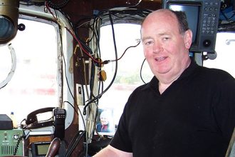 Fisherman on a fishing vessel's bridge in a commercial fishing industry setting.
