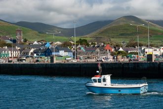 Fishing vessel docked at port with hills in background, commercial fishing industry publication.