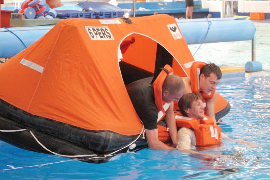 Fishing vessel with orange rescue tent in a port, commercial fishing industry context.
