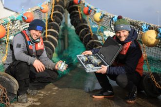 Fishermen with gear on a fishing vessel, preparing for a commercial fishing operation in Ireland.
