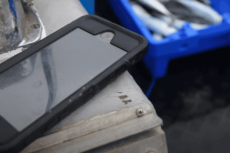 Smartphone on fishing vessel equipment in a commercial fishing industry setting.