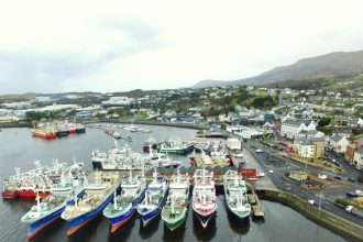 Fishing vessels docked at port in a coastal town, commercial fishing industry scene.