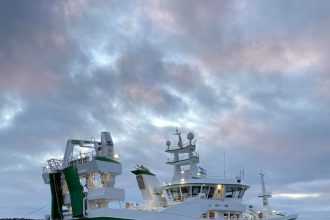 Large fishing vessel docked at port with gear and industry equipment visible in a commercial fishing.