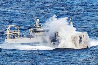 Fishing vessel navigating rough seas in commercial fishing industry context.