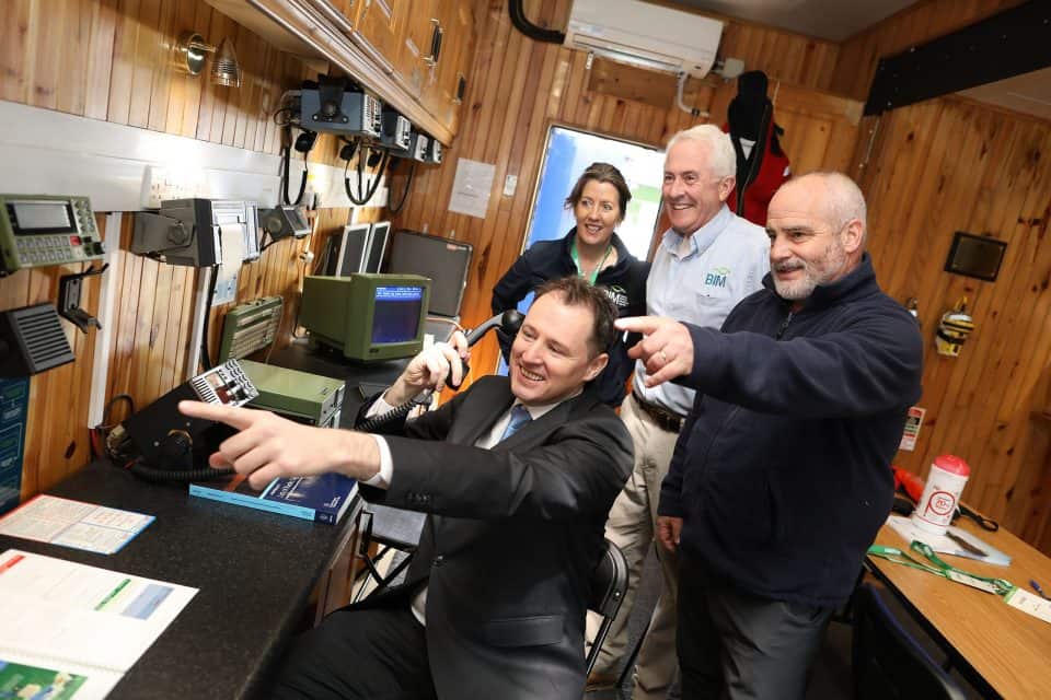 Fishermen and crew in a control room of a fishing vessel discussing operations, industry equipment,.