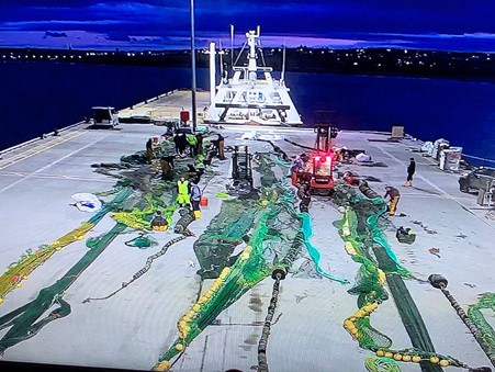 Fishing vessel with gear and crew preparing for operation at port in a commercial fishing industry.