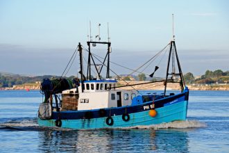 Fishing vessel with gear and equipment in a port, commercial fishing industry publication.