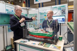 Two men discussing a fishing vessel model at a commercial fishing industry exhibition.