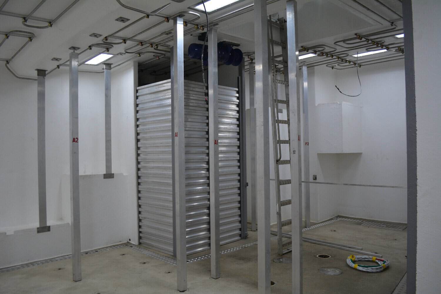 Interior of a fishing vessel's processing area with industry equipment and storage racks.