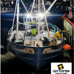 Commercial fishing vessel at Killybegs port with crew handling gear at night, industry equipment in.