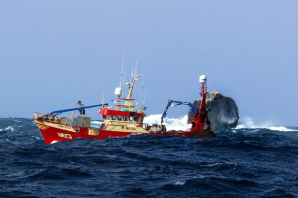 Fishing vessel with gear and equipment navigating rough sea in commercial fishing industry.