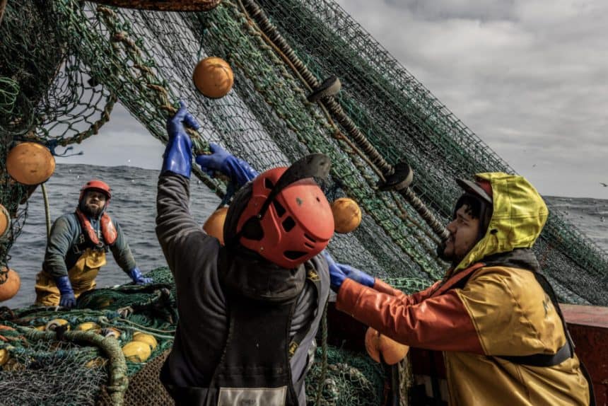 Commercial fishing vessels handling fishing gear at port, industry equipment, and catches in the sea.
